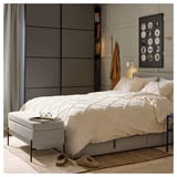 Gezellige slaapkamer met wit beddengoed, zwart framebed, grijze kledingkast, muts, slippers en kunst aan de muur.