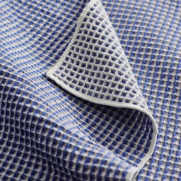 Gevouwen blauw-witte wafelgeweven handdoek, met ingewikkelde ruitpatronen, met een gestructureerde, zachte uitstraling.