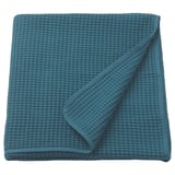 Een VÅRELD sprei in blauw, gemaakt van 100% katoen. Het is gevouwen met een gestructureerd weefsel, ideaal voor decoratie en warmte.