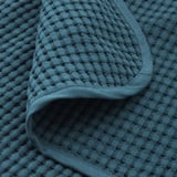 Blauwe getextureerde katoenen sprei, close-up met zacht weefsel en gezellige textuur.