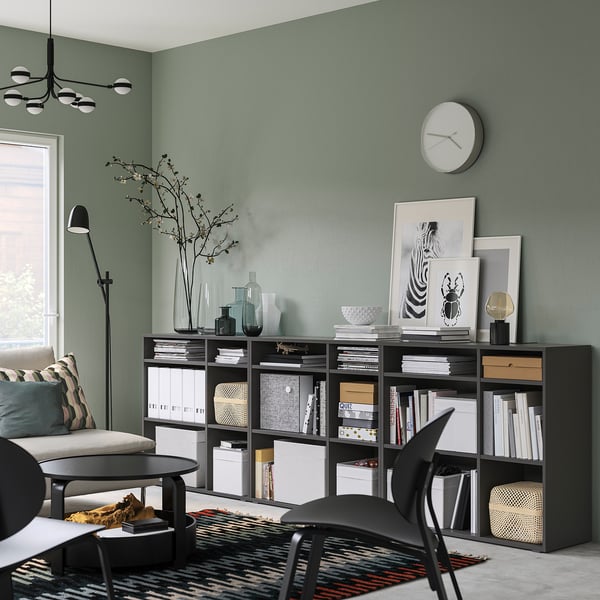 Modern woongedeelte met VIHALS grijze opbergmeubels. Klok aan de muur, zwarte meubels, gezellige zitplaatsen, tapijt met patroon. Groene muren, wit decor.