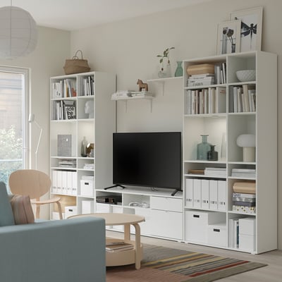 Moderne woonkamer met witte VIHALS opbergmeubels, tv, blauwe bank en kleurrijk vloerkleed.
