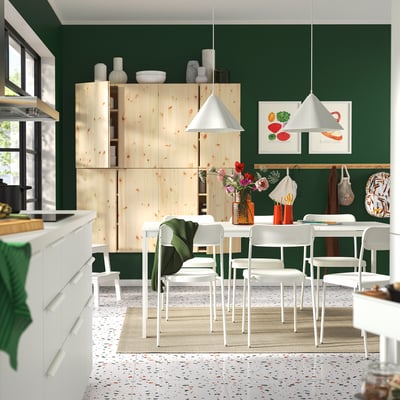 Moderne keuken met groene muren, houten kast, witte eethoek, terrazzovloer en decoratieve artikelen.