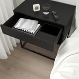 Zwart nachtkastje met open lade met boeken. Soft-closing functie gemarkeerd.
