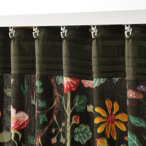 Zwarte gordijnen met kleurrijke bloemenprints hangen aan witte haken, waardoor lichtregeling en privacy mogelijk zijn.