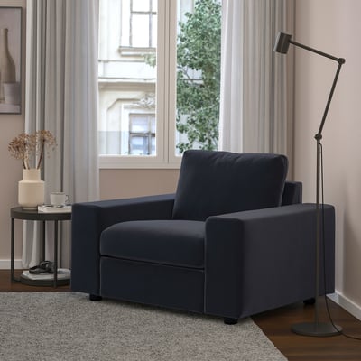 Gezellige woonkamer met een marineblauwe VIMLE fauteuil, bijpassende bijzettafel en hoge vloerlamp bij breed raam.