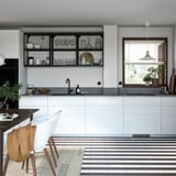 Moderne keuken met witte hoogglans kasten, open planken, grijs aanrechtblad en gestreepte vloertegels.