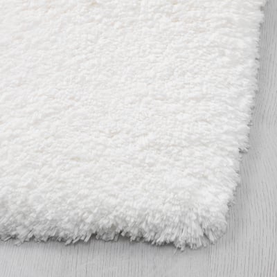 A white ALMTJÄRN bath mat, rectangular, with a soft microfibre top, and a latex backing for grip.