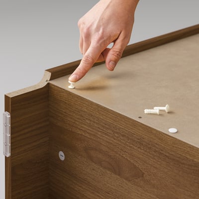 Person assembling BILLY wooden furniture, securing parts with white fasteners.