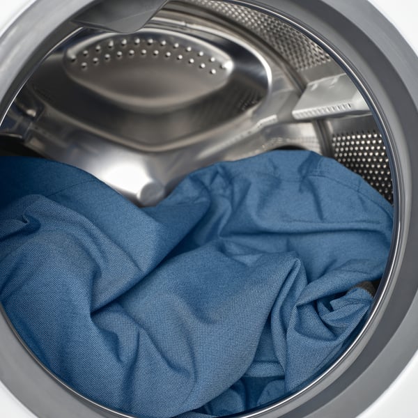 A washing machine drum with blue jeans inside, illustrating the ease of washing machine-compatible laundry.