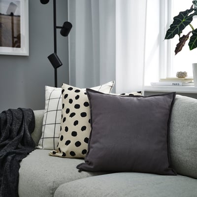 Grey GURLI pillow on couch, circular design, bright room with natural light.