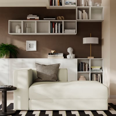 JÄTTEBO beige modular sofa with black/white pillow, chaise, shelves with books/decor, lamp, rug, side table.