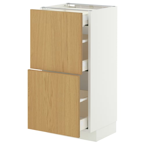 An IKEA METOD kitchen cabinet with light wooden doors and white sides. It includes multiple drawers and has a modern design.