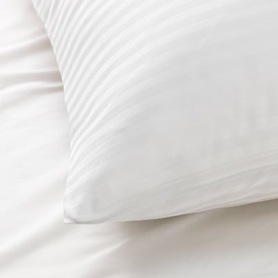 Close-up of luxurious, smooth white pillowcase with subtle striped texture, showcasing high-quality fabric.