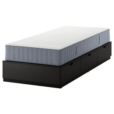 A black NORDLI bed frame with three drawers and a white mattress. It is a space-saving solution with built-in storage.