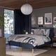 Modern bedroom with RÅHOLMAR bed, blue-grey, wooden, square, geometric print bedding, hanging lamp, dark curtains, art, plants, cosy.