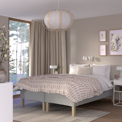 Serene bedroom with RÅHOLMAR bed, grey frame, beige bedspread, white pillows, large window, pendant light, pink lamp, framed art.
