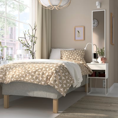 Modern bedroom with bed, pillows, bedside table, mirror, and sheer curtains.
