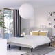 Modern bedroom with RENFJÄLLET bed, grey headboard, yellow pillows, large pendant lamp, tall windows, art, plant, black & white rug.
