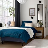 Blue & white RENFJÄLLET bed, bedside table, plants, decor, cosy lighting.