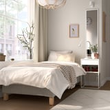 Minimalist bedroom with white bed, neat decor, plant, art, & natural light