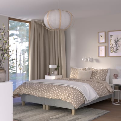 Bedroom with RENFJÄLLET bed; modern design, light colours, geometric bedding, large window, leafy view, wooden floor.