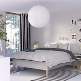Modern bedroom with RISHÖJDEN white polka dot bed, black decor, striped curtains, rug, and bedside table lamp.