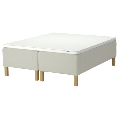 A white rishojden mattress on a beige fabric base with wooden legs.