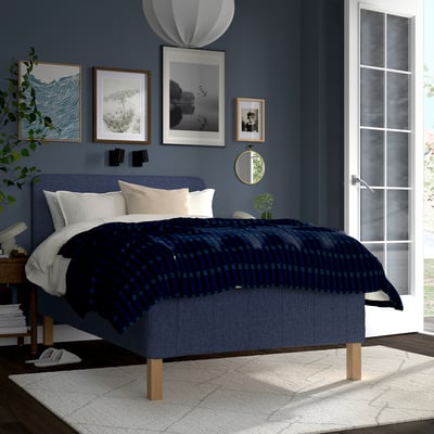 Modern bedroom with RISHÖJDEN bed, dark blue blanket, white pillows, wall art & plants.