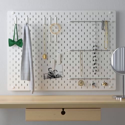 SKÅDIS white pegboard display with accessories like jewellery, cloth, and photo. Mounted above wood drawer, ideal for organising small items.