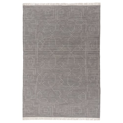Depicts a grey TÅRGRÄS handwoven wool rug with a geometric pattern and fringed edges.