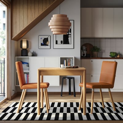 Modern dining area with TONSTAD wooden table and brown leather chairs, black & white chequered rug, stylish hanging lamp.