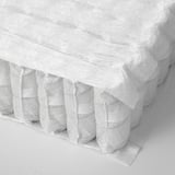 Close-up of a rolled mattress showing visible comfort zones, indicating quality support.