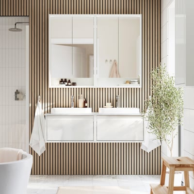 Modern bathroom with ÄNGSJÖN white vanity, double sinks, striped wall, and mirror; large plant beside it.