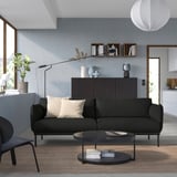 Modern living room with grey sofa, black coffee table, plants, and blue walls.