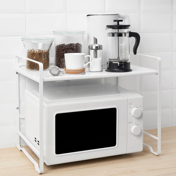 White kitchen shelf over microwave, holding coffee, jars, and maker.