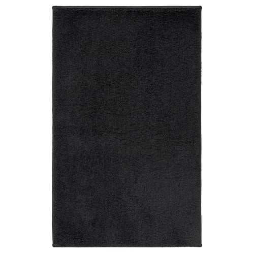A dark grey rectangular BACKMÅRA bath mat made from recycled polyester, designed for comfort and safety in the bathroom.
