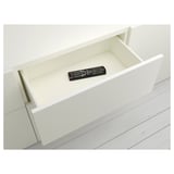 White drawer with black remote control. Part of ikea BESTÅ system for organizing small items.