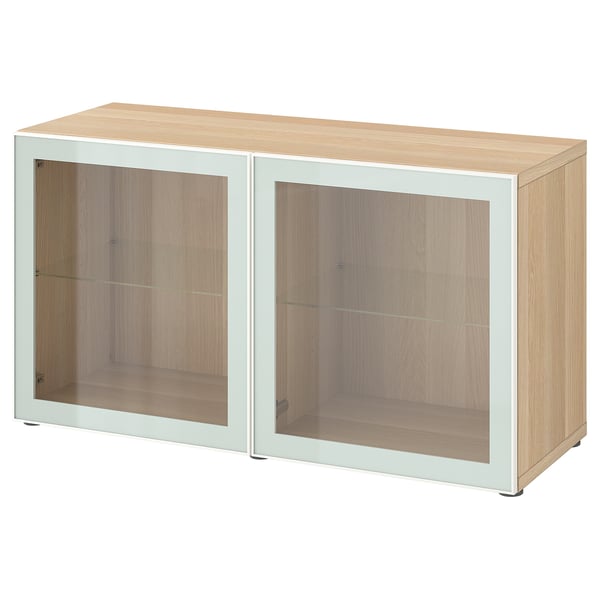 Modern BESTÅ cabinet in light oak. Two glass doors with minimalist handles. Rectangular, light-colored design.