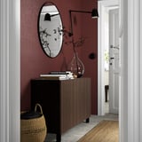 BESTÅ sideboard with mirror, lamp, and decor in dark room.