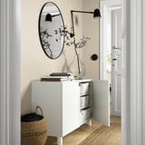 Modern white sideboard with shelves, drawers, mirror, lamps, and vase.