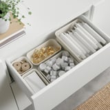 Open drawer with organised stationary: pens, tape, paper clips, ribbon, and candles.