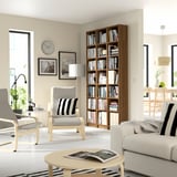 Modern living room with BILLY bookcase, beige sofa, wooden table, grey chairs, large window, black-and-white decor.