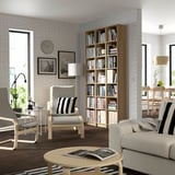 Modern living room with BILLY bookcase, books, grey chairs, beige couch, wood floor, large windows.