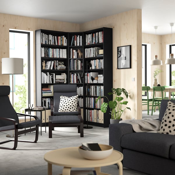 Modern living room with BILLY bookcase, armchair, coffee table, and grey sofa bathed in natural light.