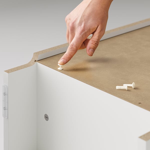 Person assembling white IKEA BILLY bookcase using screws.