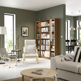 Modern living room with BILLY bookcase, chair, sofa, coffee table, green walls.