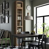 Modern dining area with BILLY bookcase, clock, table & chairs, pendant light, sofa, green stool, picture gallery.