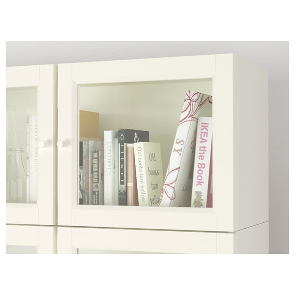 White BILLY bookcase with glass doors. Books are neatly arranged on shelves.