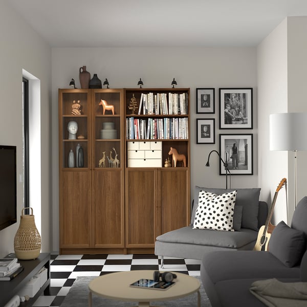 Modern living room with BILLY wooden bookshelf, grey sofa, black-and-white chequered floor, and various decorative items.